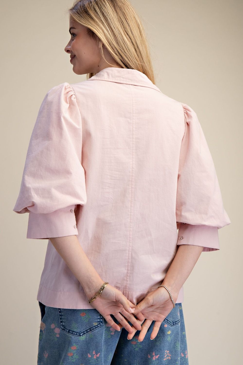 Person wearing a light pink blouse with puffed sleeves on a plain background