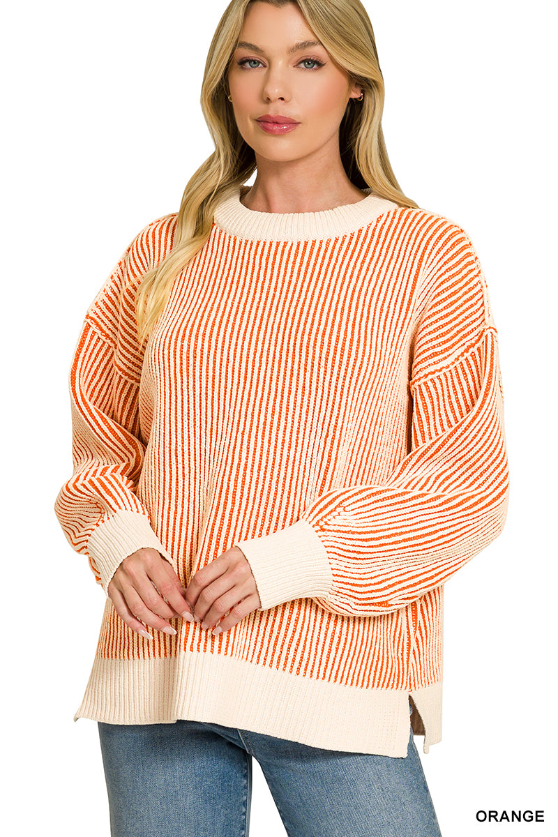A woman wearing a long-sleeve knit sweater with vertical orange and cream stripes, paired with blue jeans, against a plain white background.