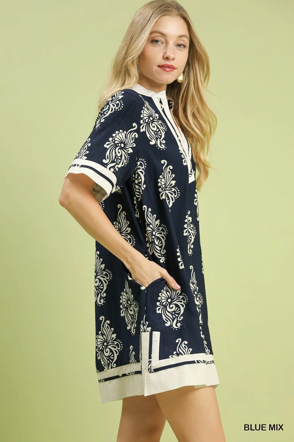 Woman wearing a navy blue dress with white patterns on a light green background