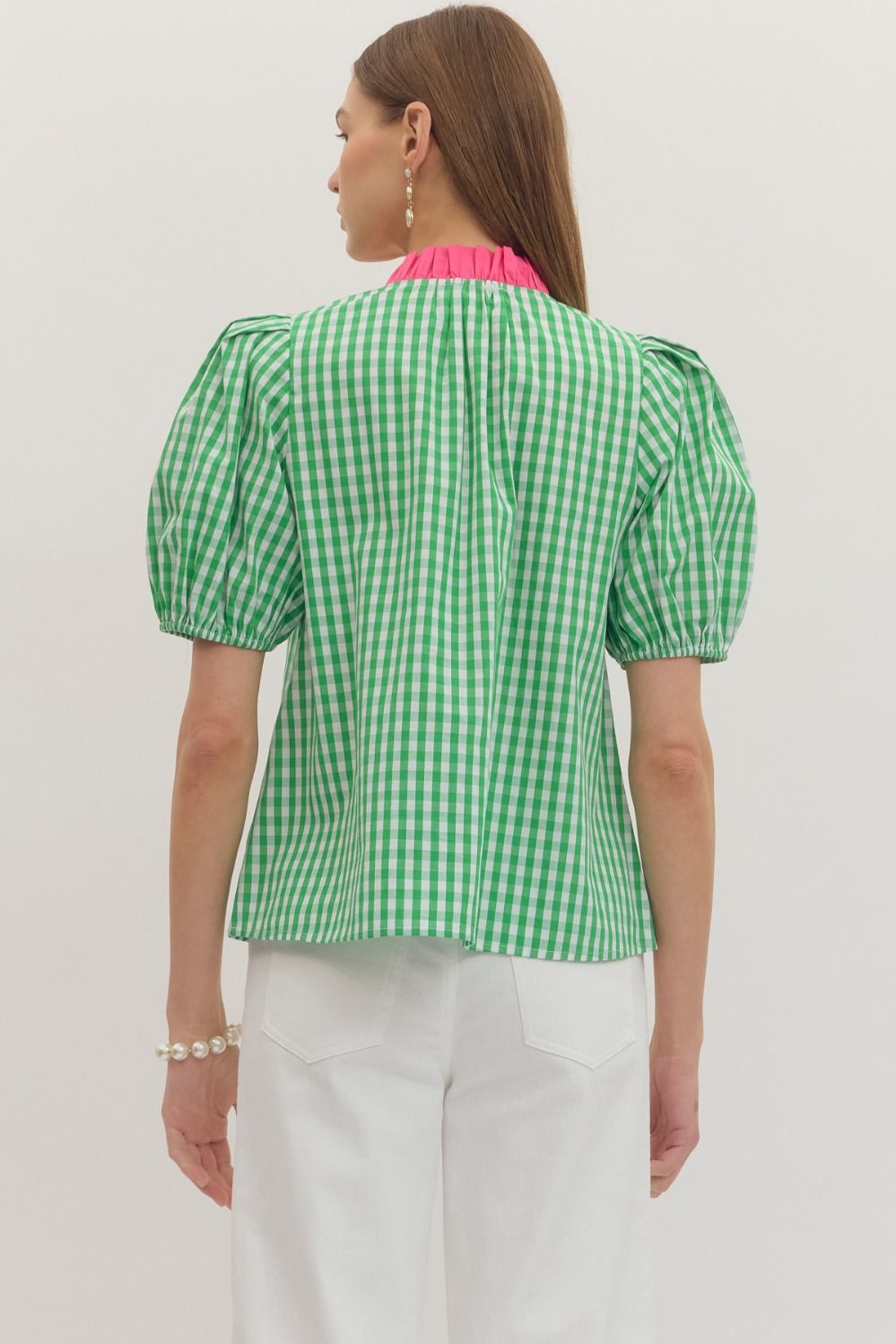 Woman wearing a green checkered blouse with pink trim on a white background