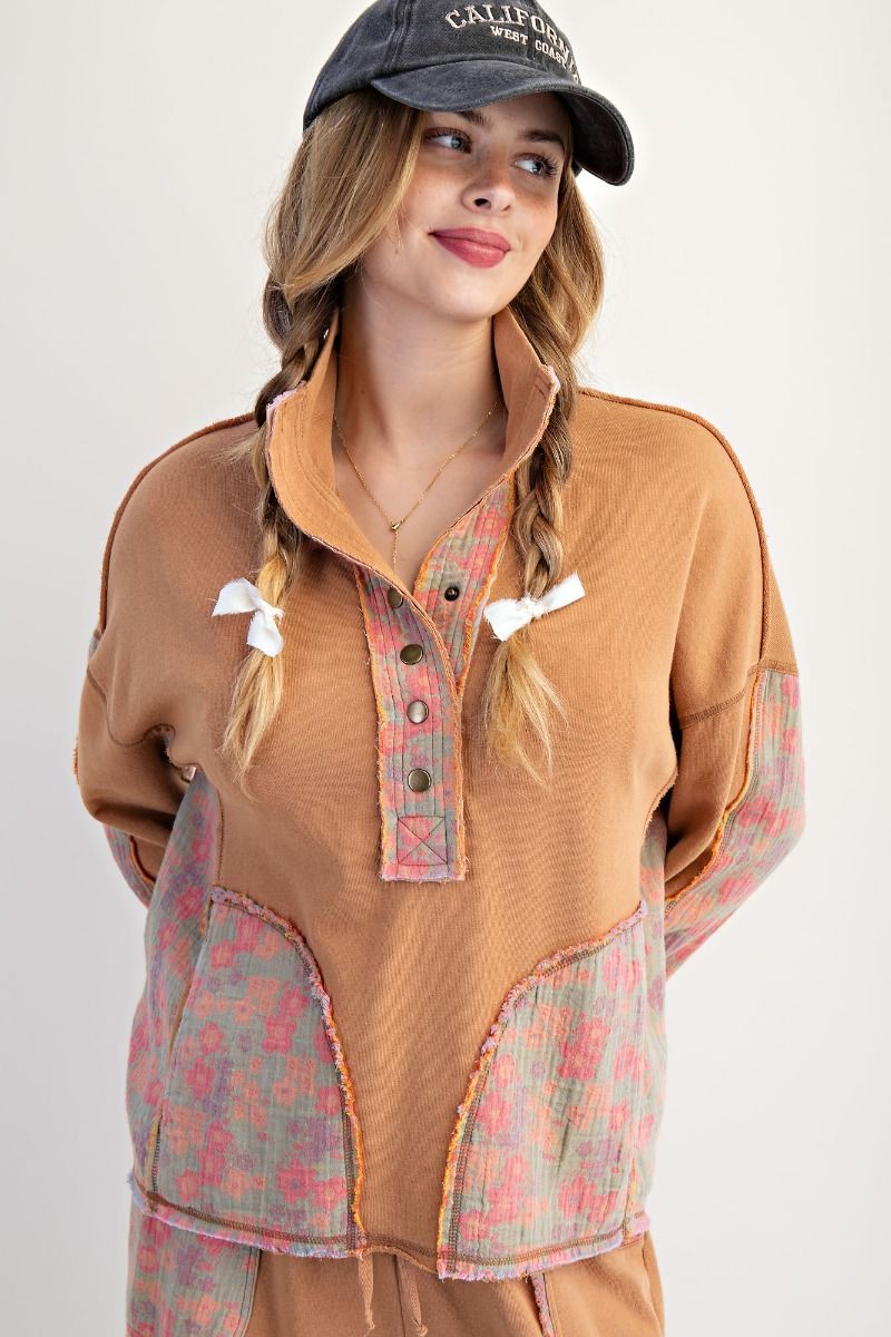 Woman wearing a brown shirt with floral patterns and a black cap on a white background