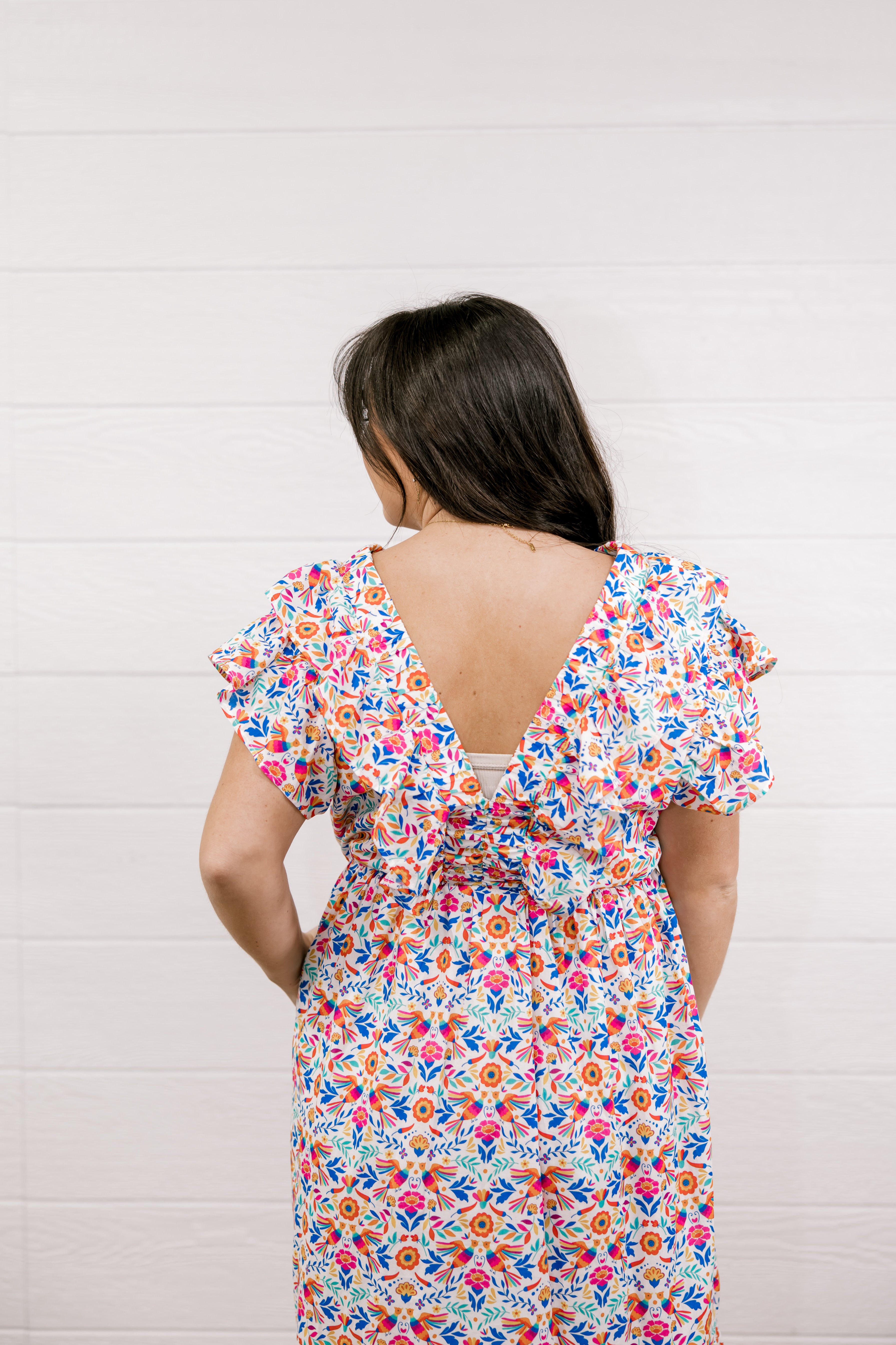 Woman wearing a colorful floral dress against a white background