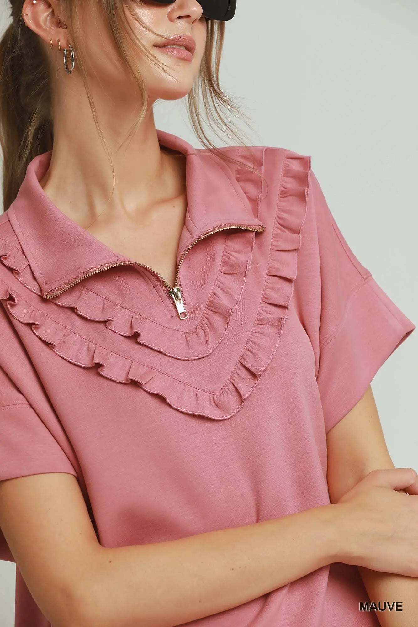 Close-up of a person wearing a mauve blouse with ruffled details.