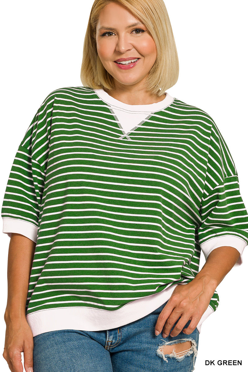 Woman wearing a green and white striped shirt with a white undershirt and blue jeans on a white background.