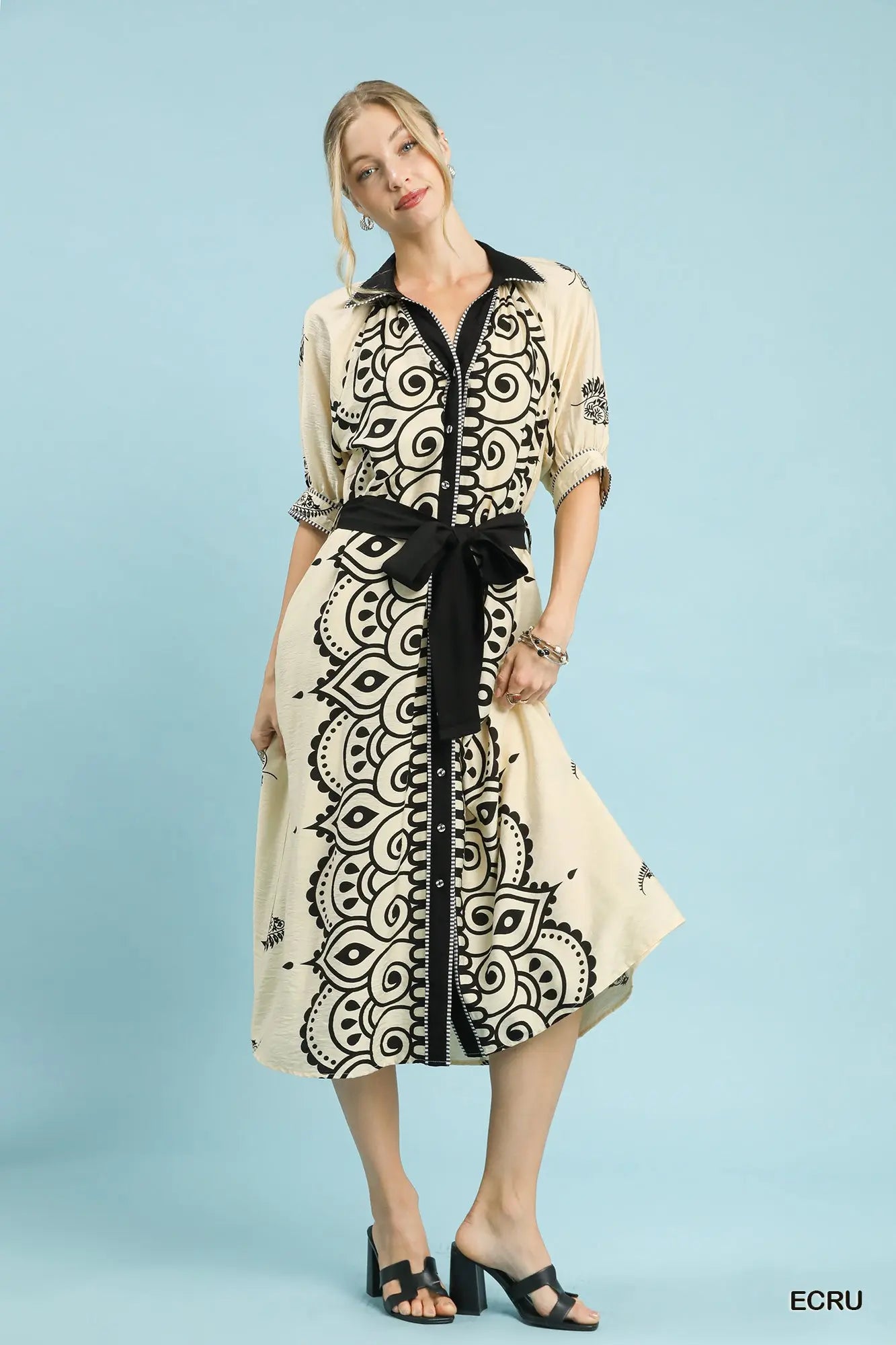 Woman wearing a beige dress with black pattern on a light blue background