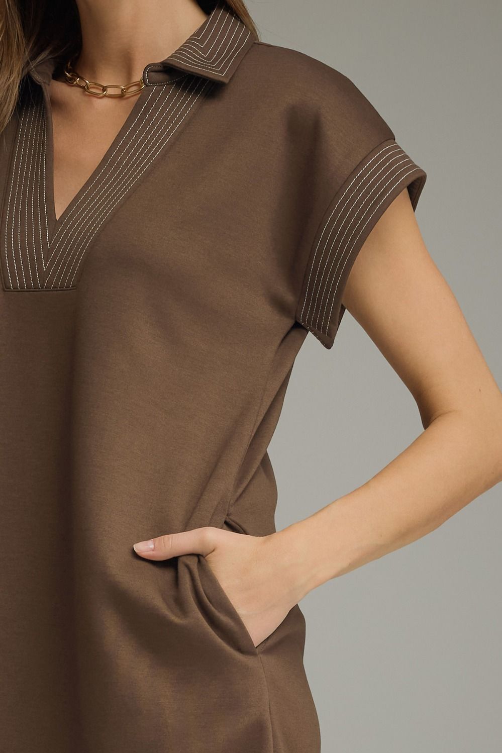 Brown dress with short sleeves and a collar on a neutral background