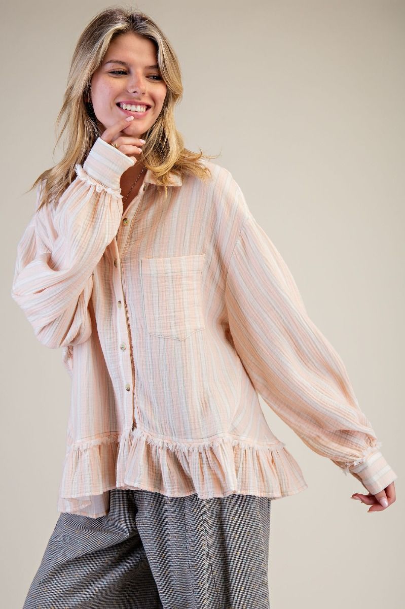 Woman wearing a light pink striped blouse with ruffled details on a plain background