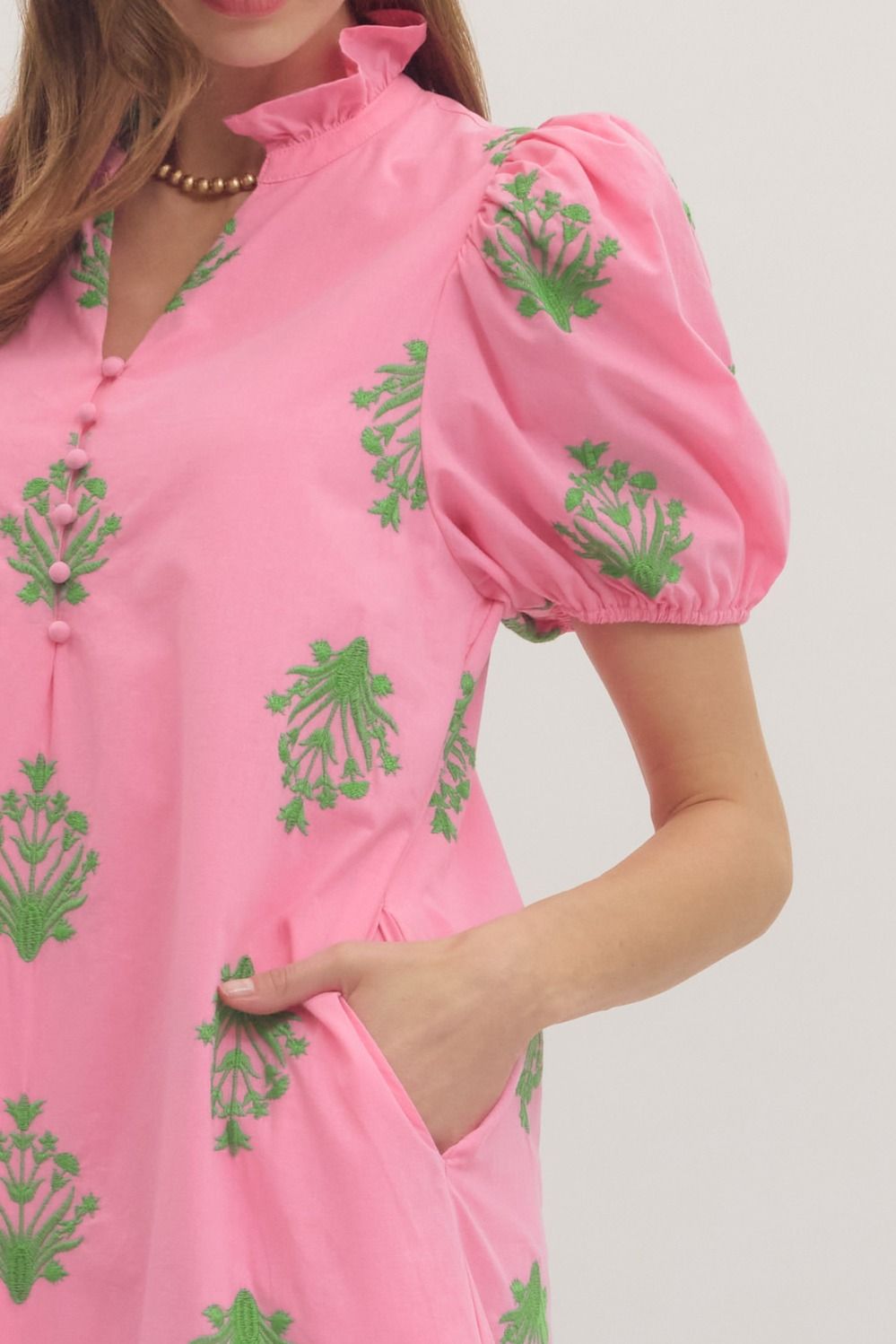 Pink dress with green floral patterns on a plain background