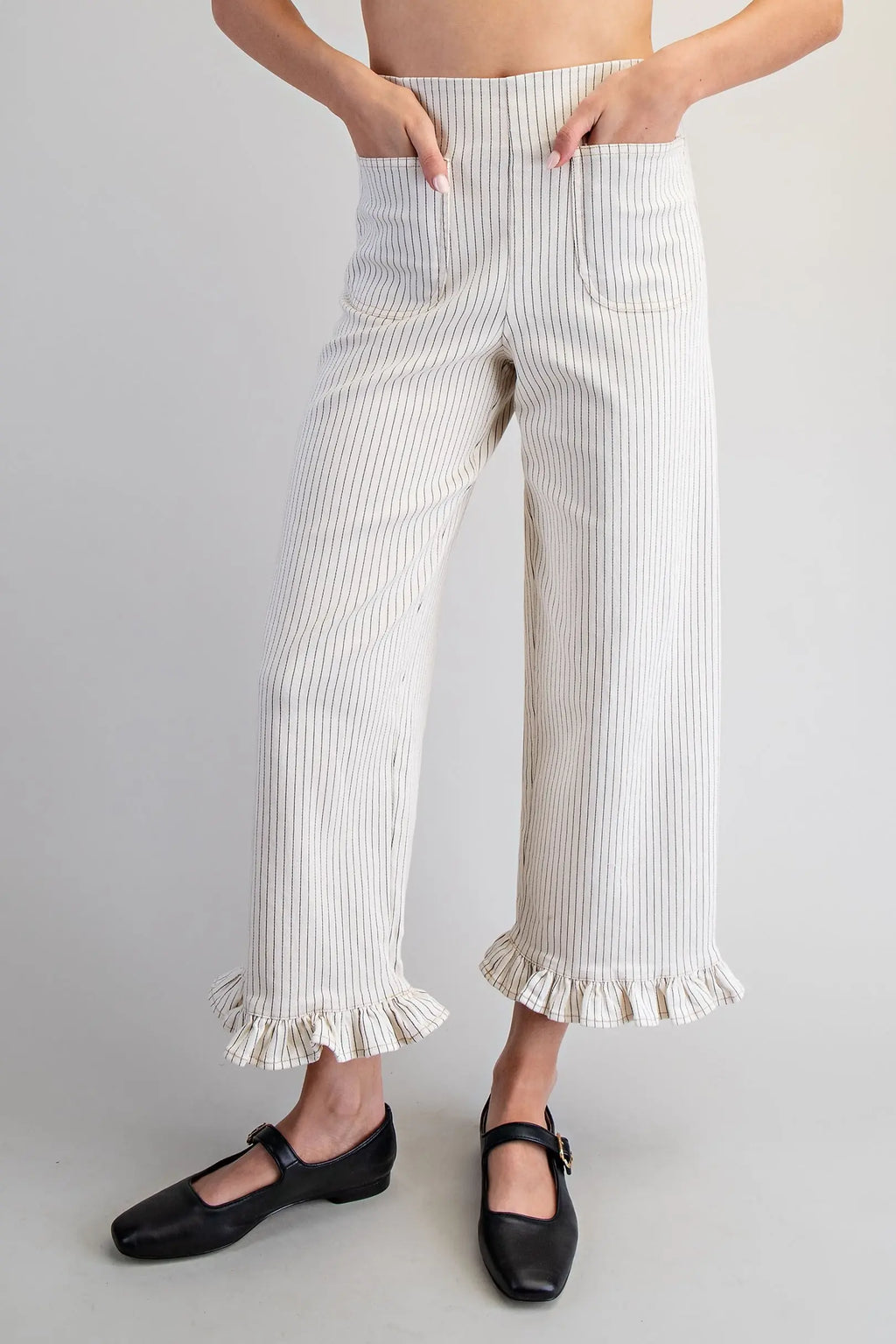 Person wearing white ruffled pants on a plain background