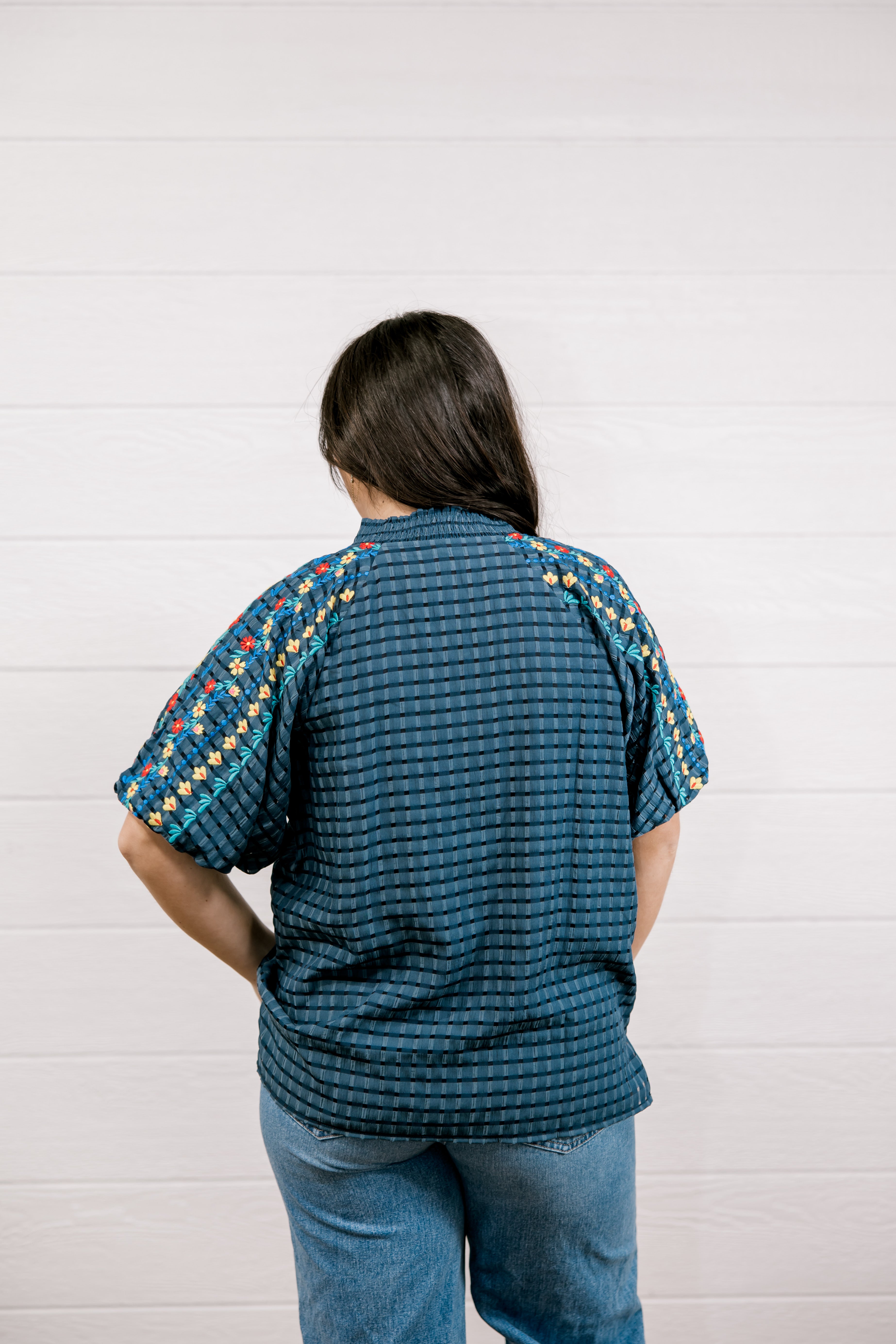 Person wearing a teal patterned shirt with colorful accents on a white background