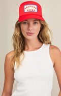 Woman wearing a red cap with 'American Grown' text on a beige background
