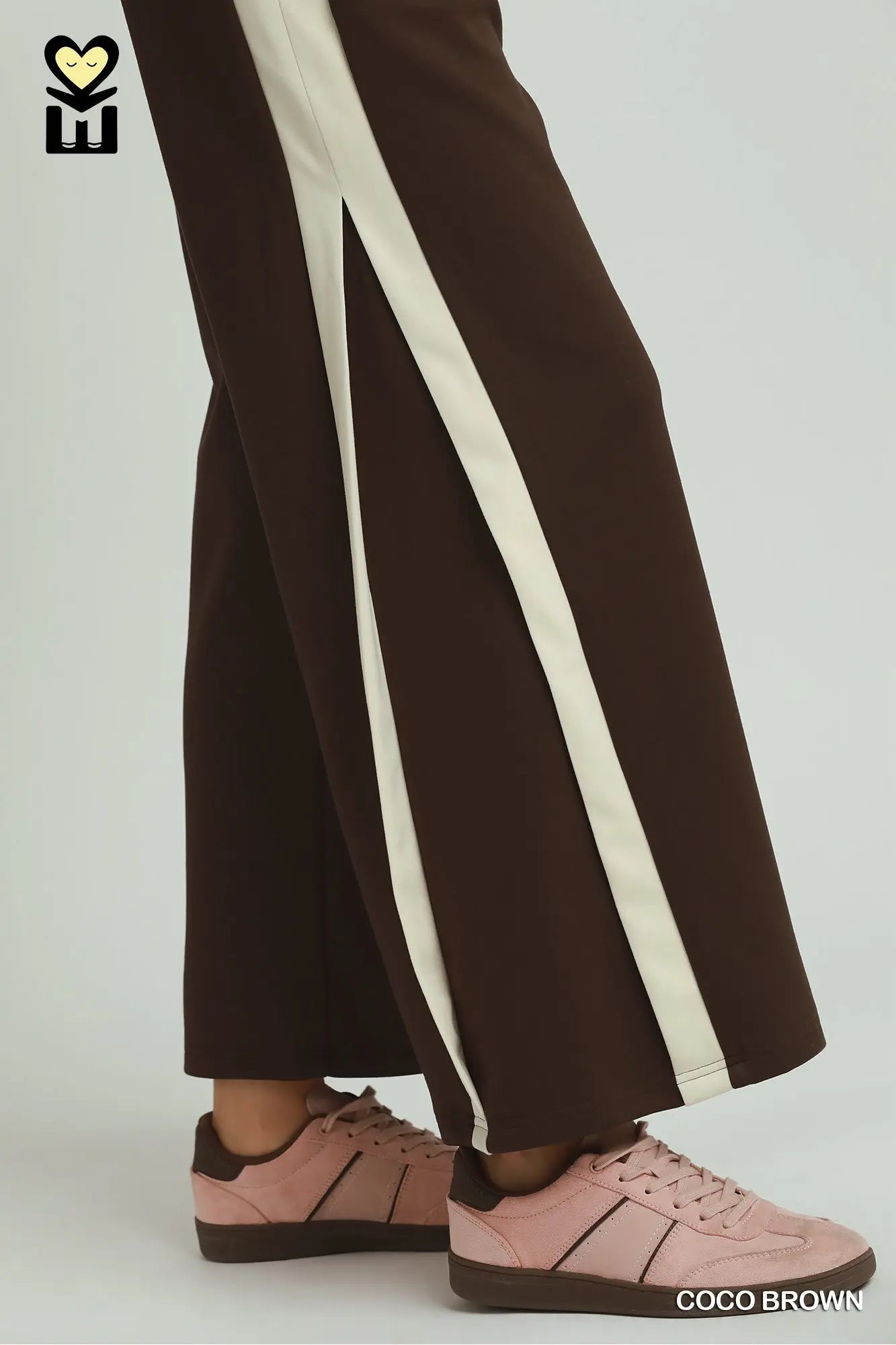 Brown pants with white stripes and pink shoes on a light gray background