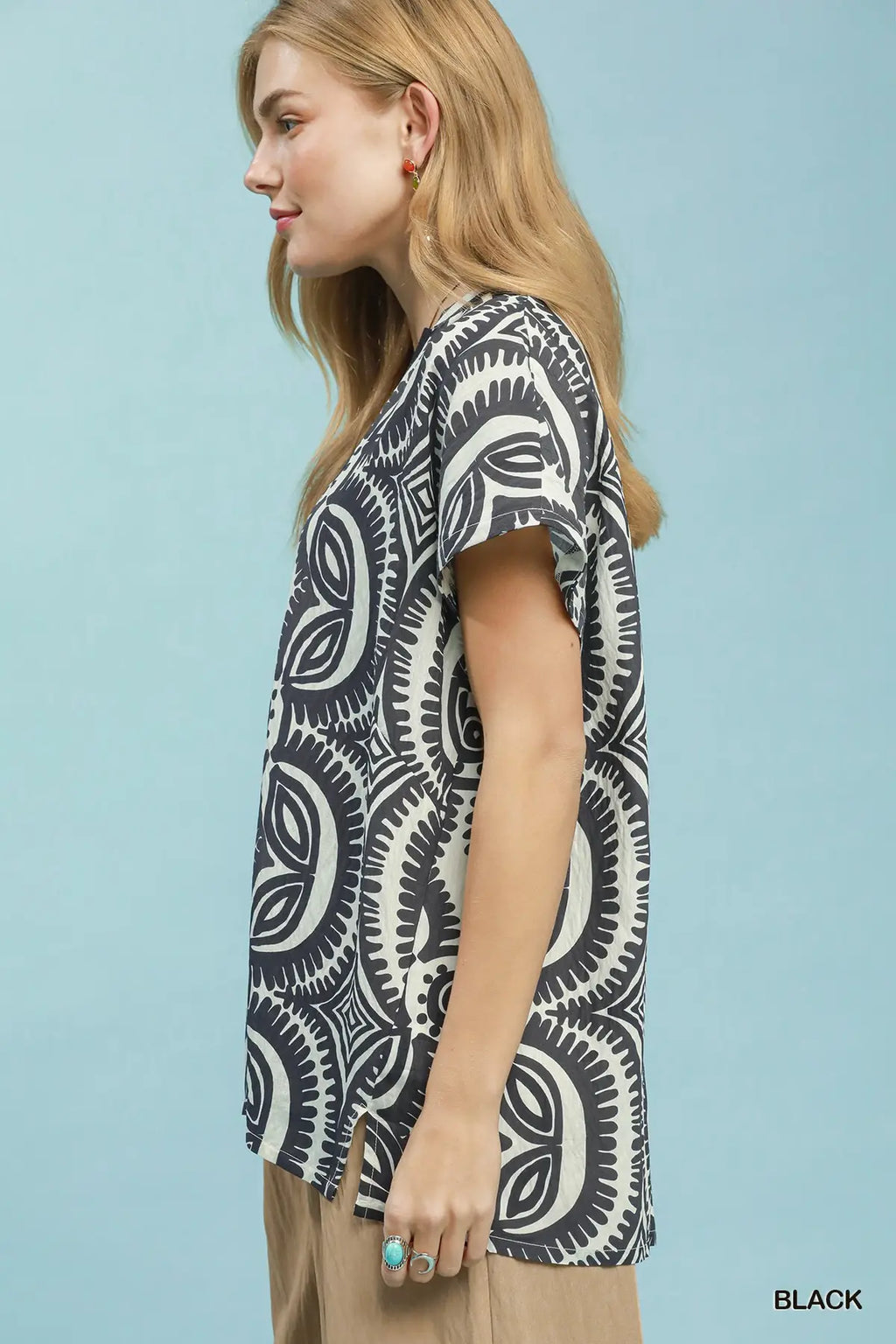 Woman wearing a black and white patterned shirt against a light blue background