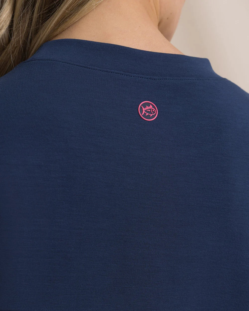 Navy blue shirt with a pink logo on a beige background