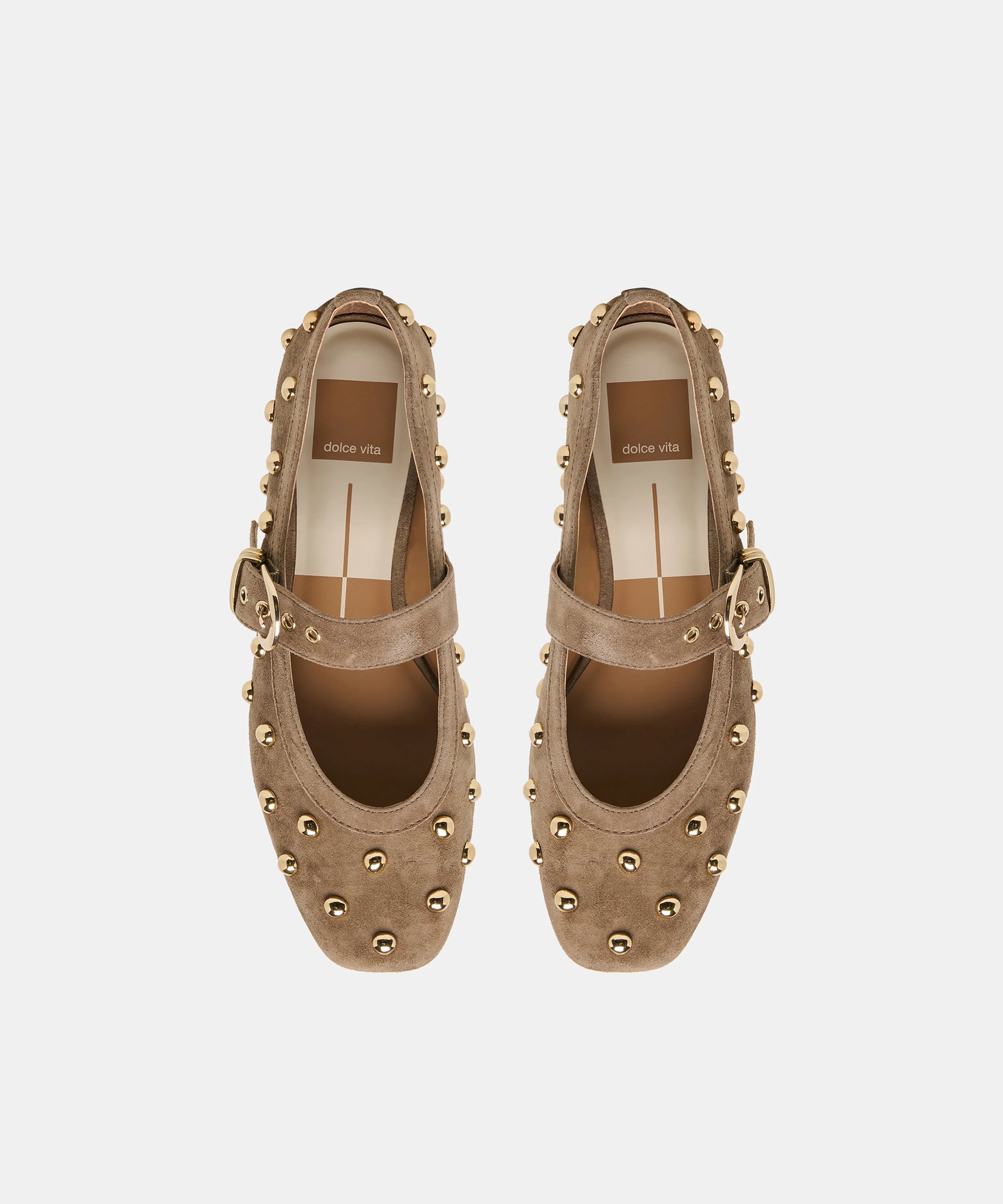 A pair of taupe-brown suede Mary Jane shoes with gold-tone studs and buckle straps, shown from a top-down view on a light gray background.
