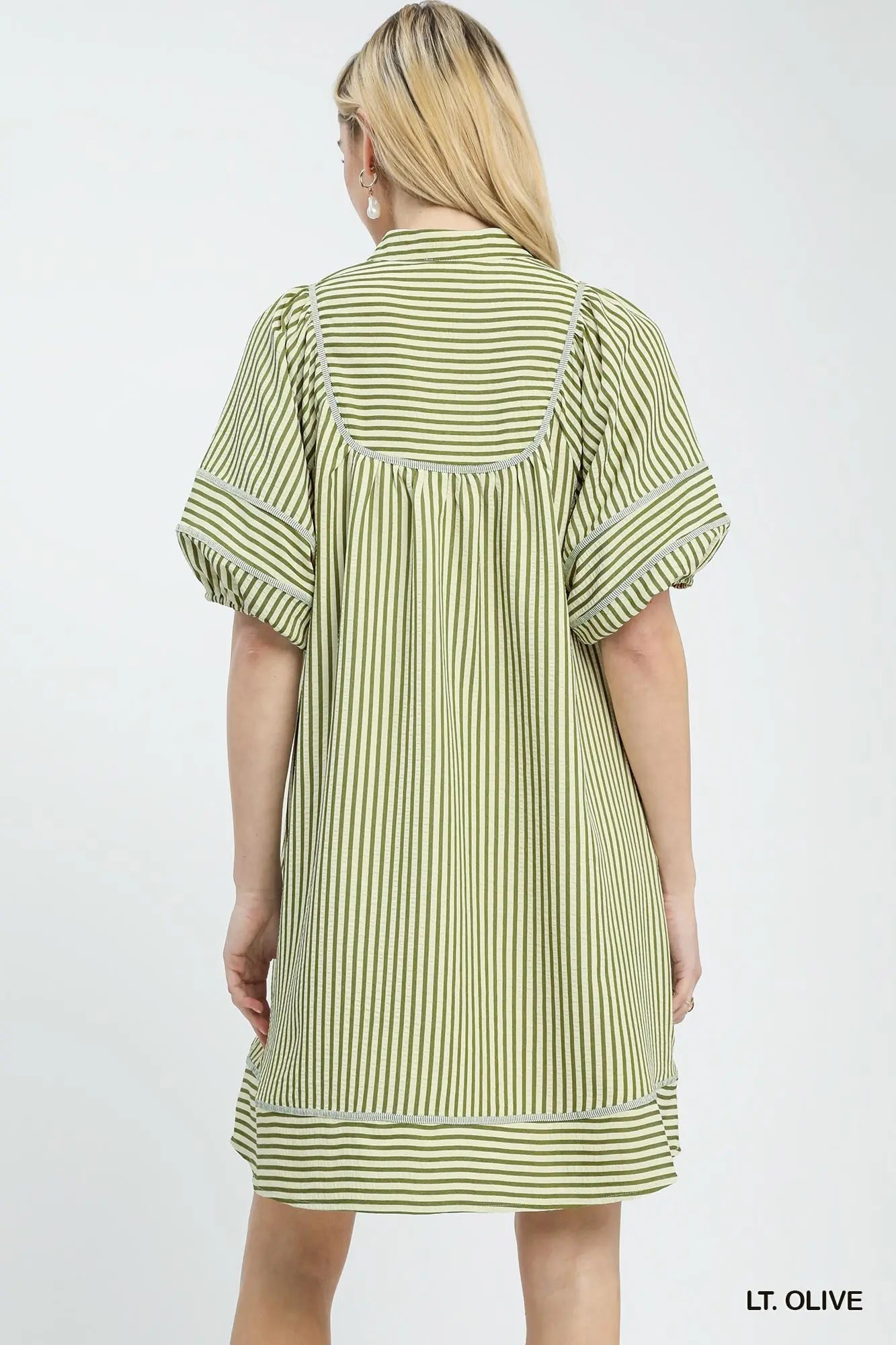 Woman wearing a light olive striped dress on a white background
