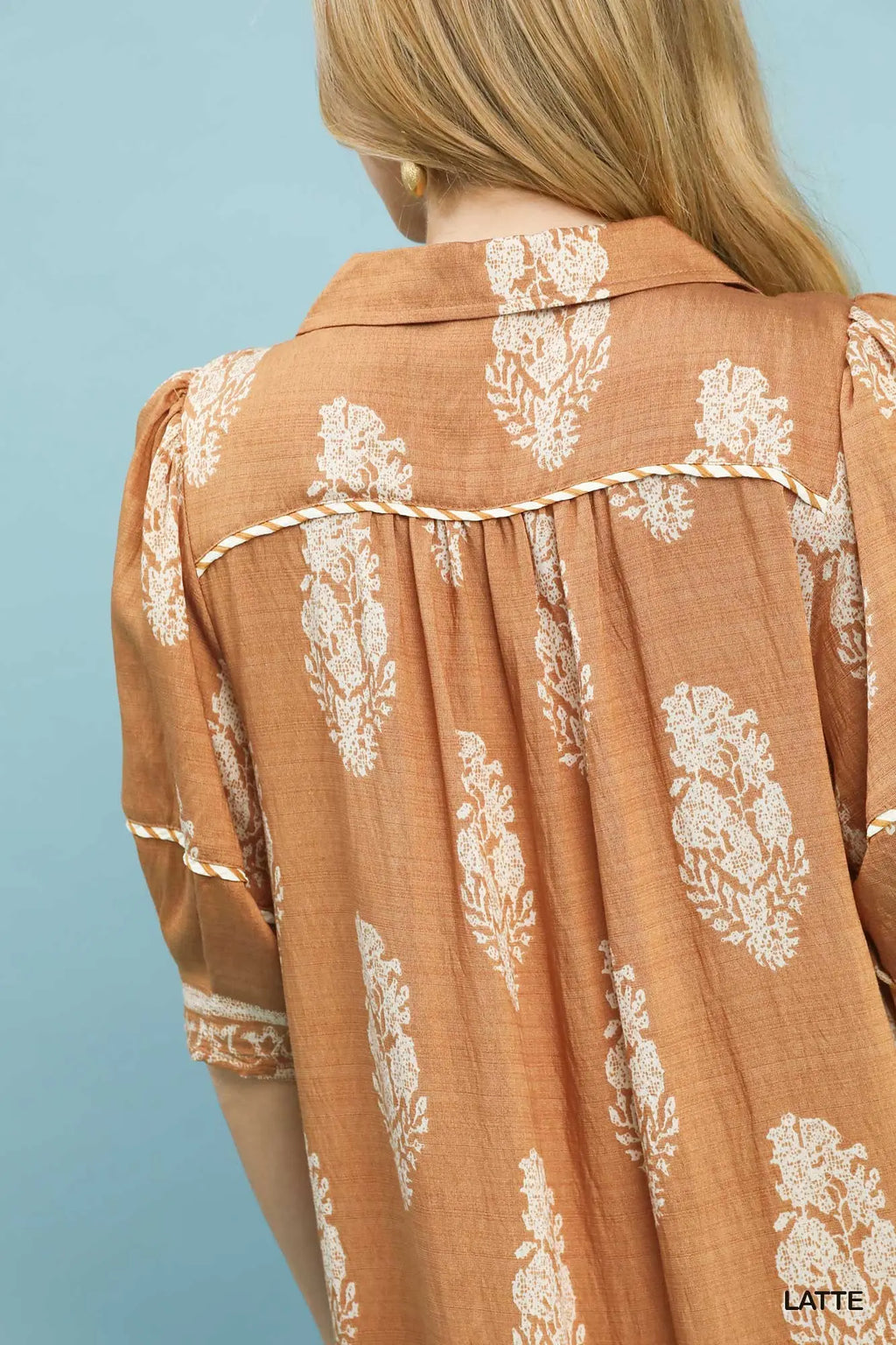 Brown blouse with white floral patterns on a light blue background