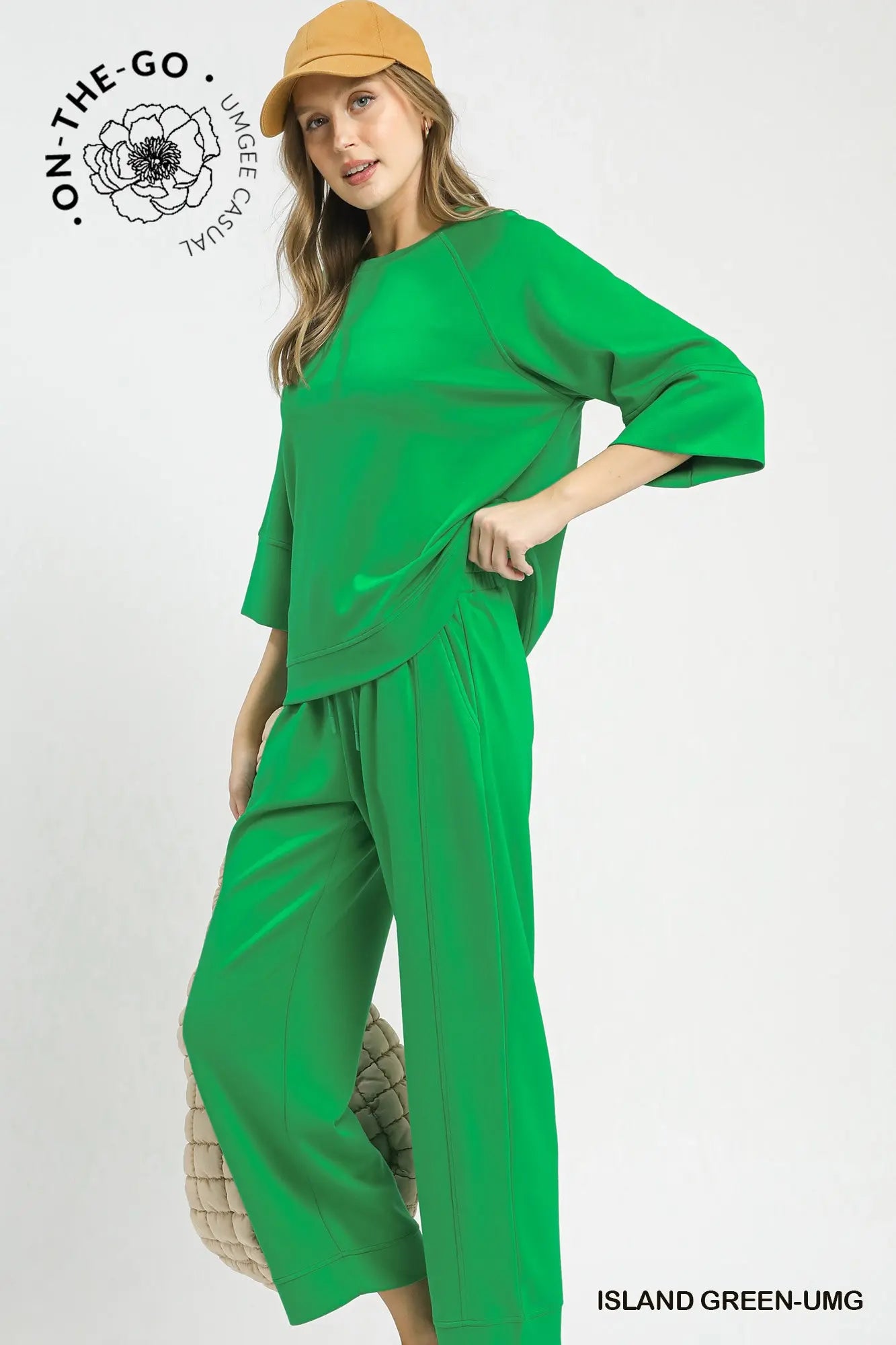 Woman wearing a green outfit with a beige hat on a white background