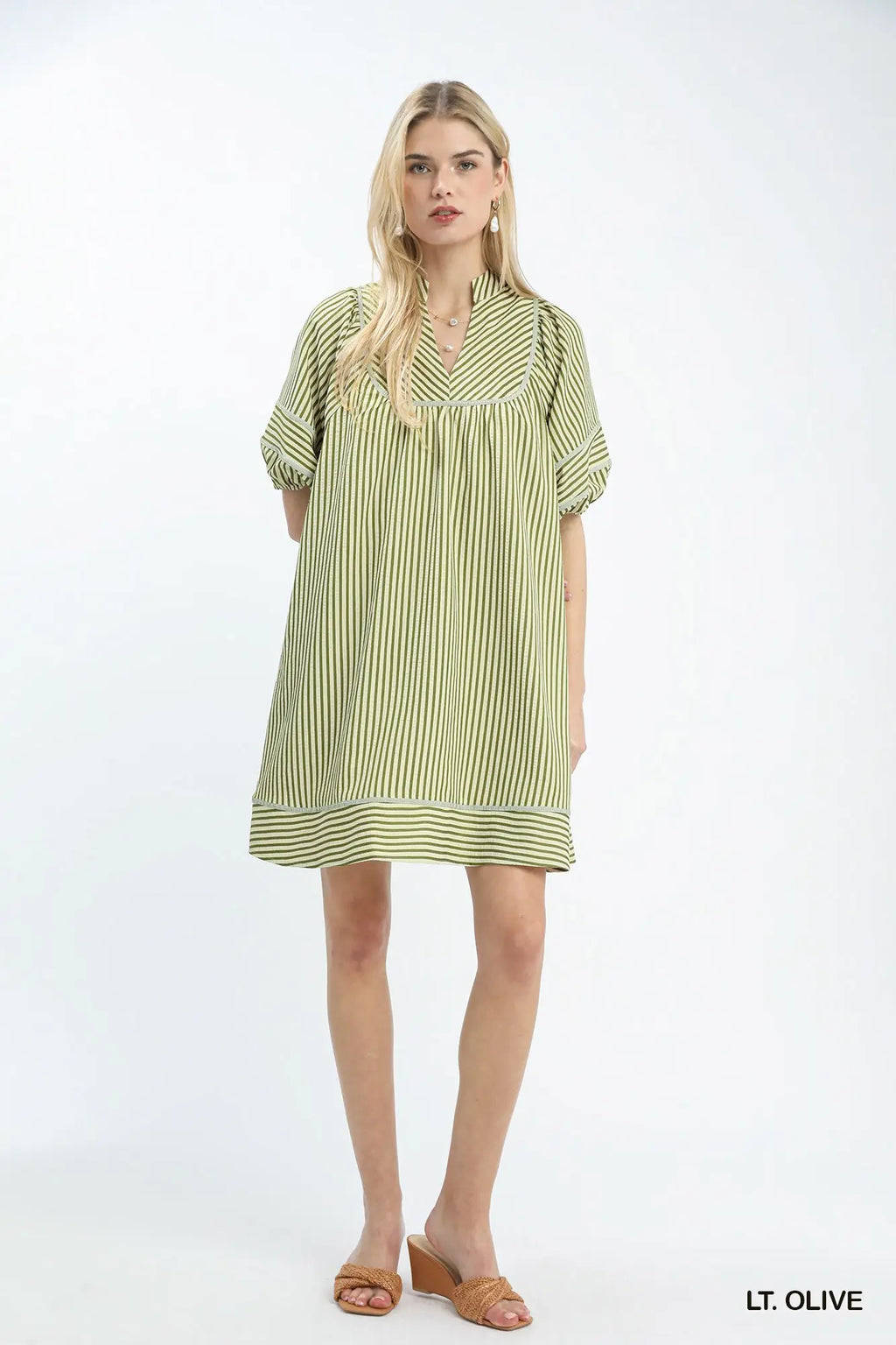 Woman wearing a light olive striped dress on a white background