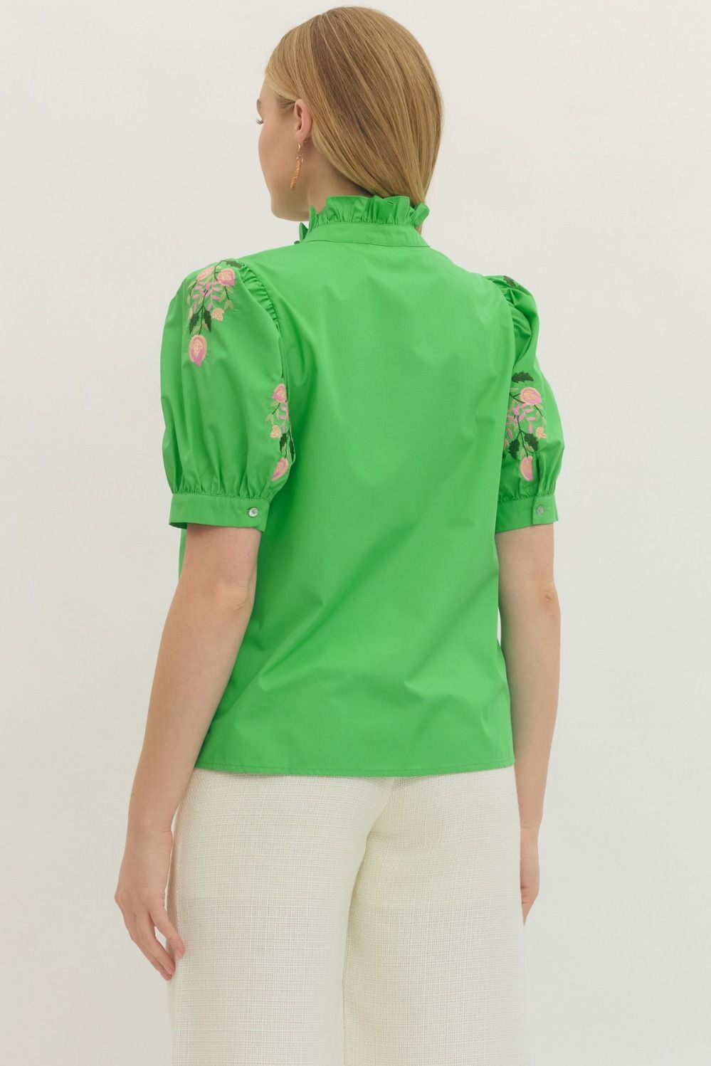 Green blouse with floral embroidery on a plain background
