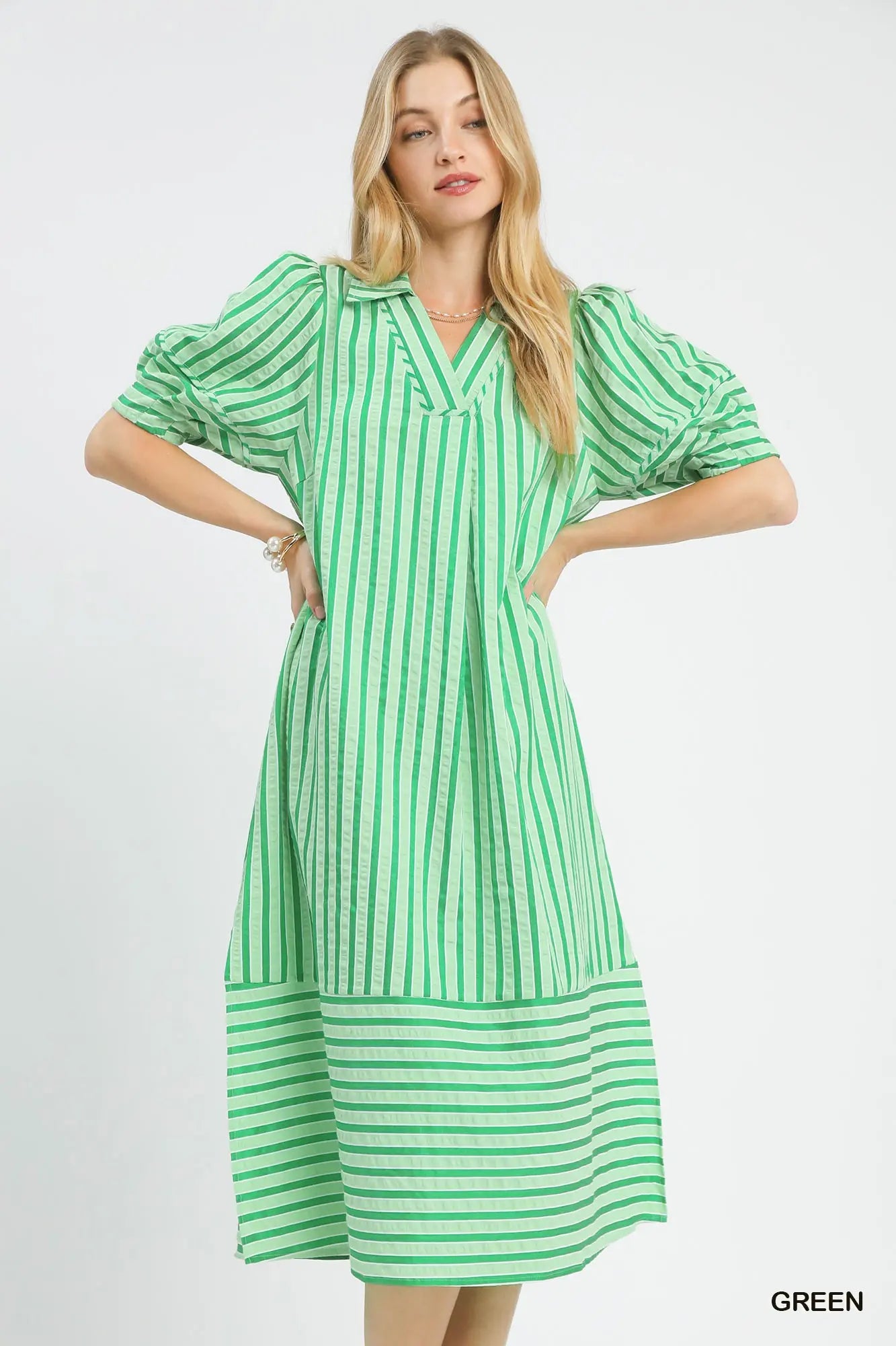 Woman wearing a green and white striped dress on a light gray background