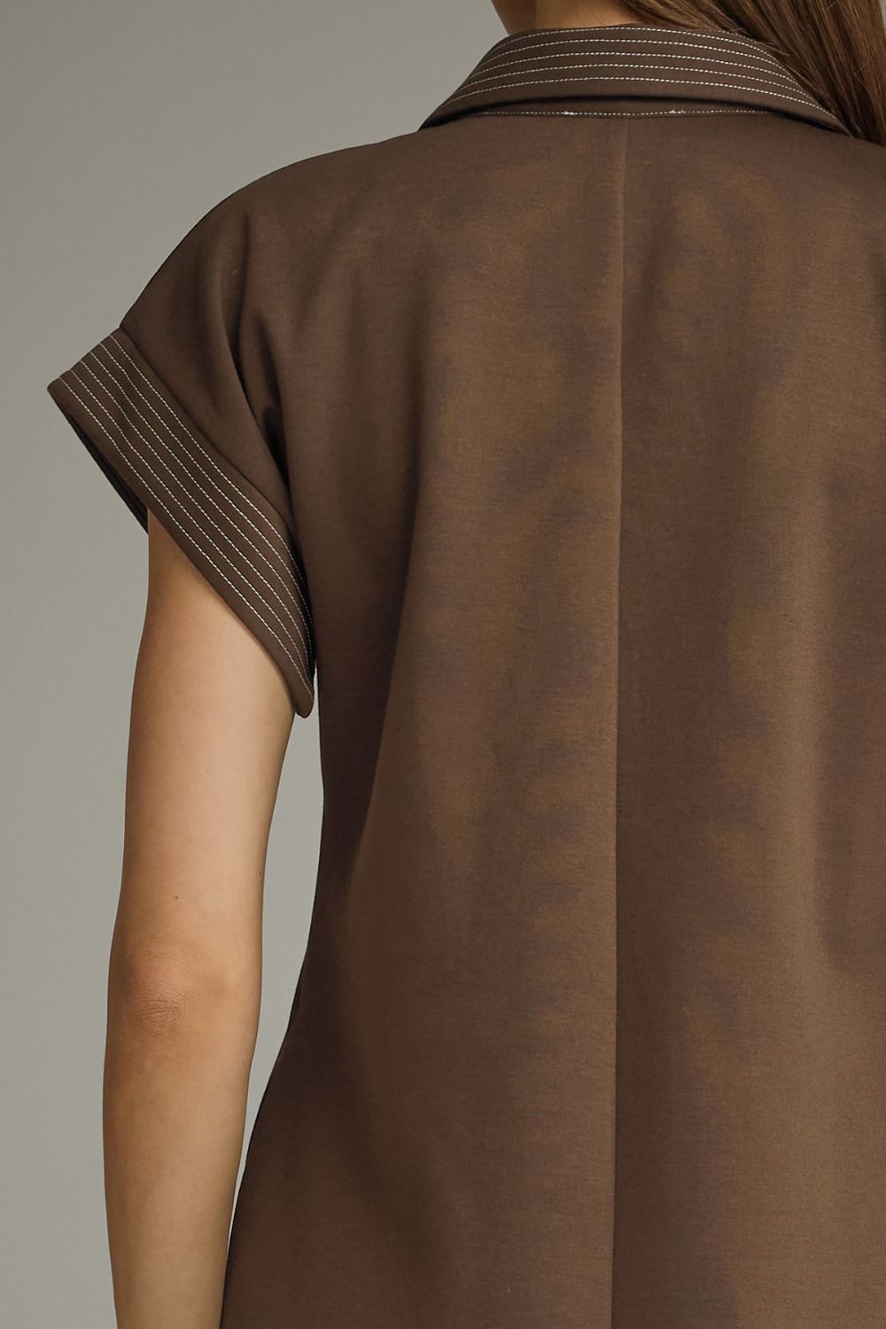 Brown shirt with striped collar on a neutral background