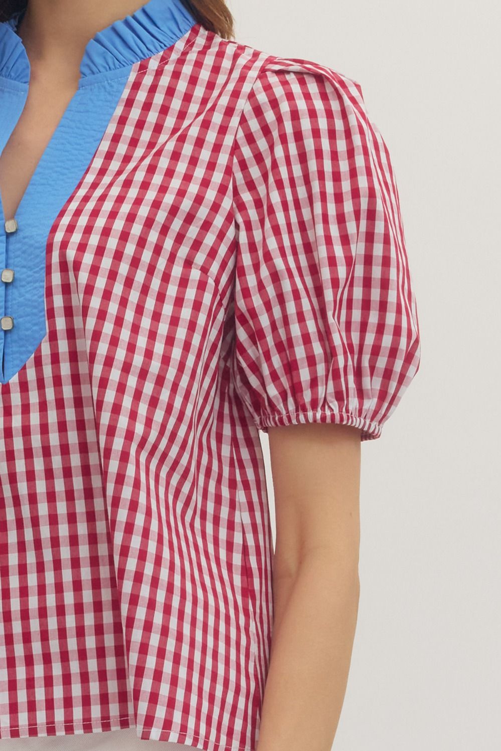 Red and white checkered blouse with blue accents on a plain background