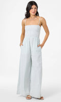 Woman wearing a light blue and white striped jumpsuit on a white background