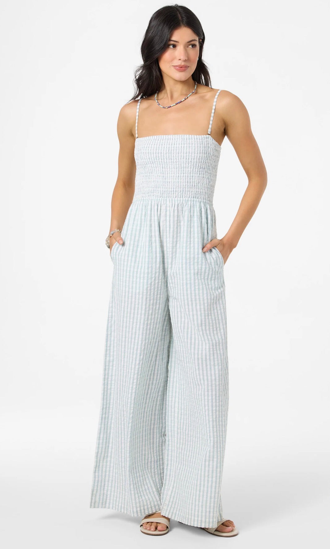 Woman wearing a light blue and white striped jumpsuit on a white background