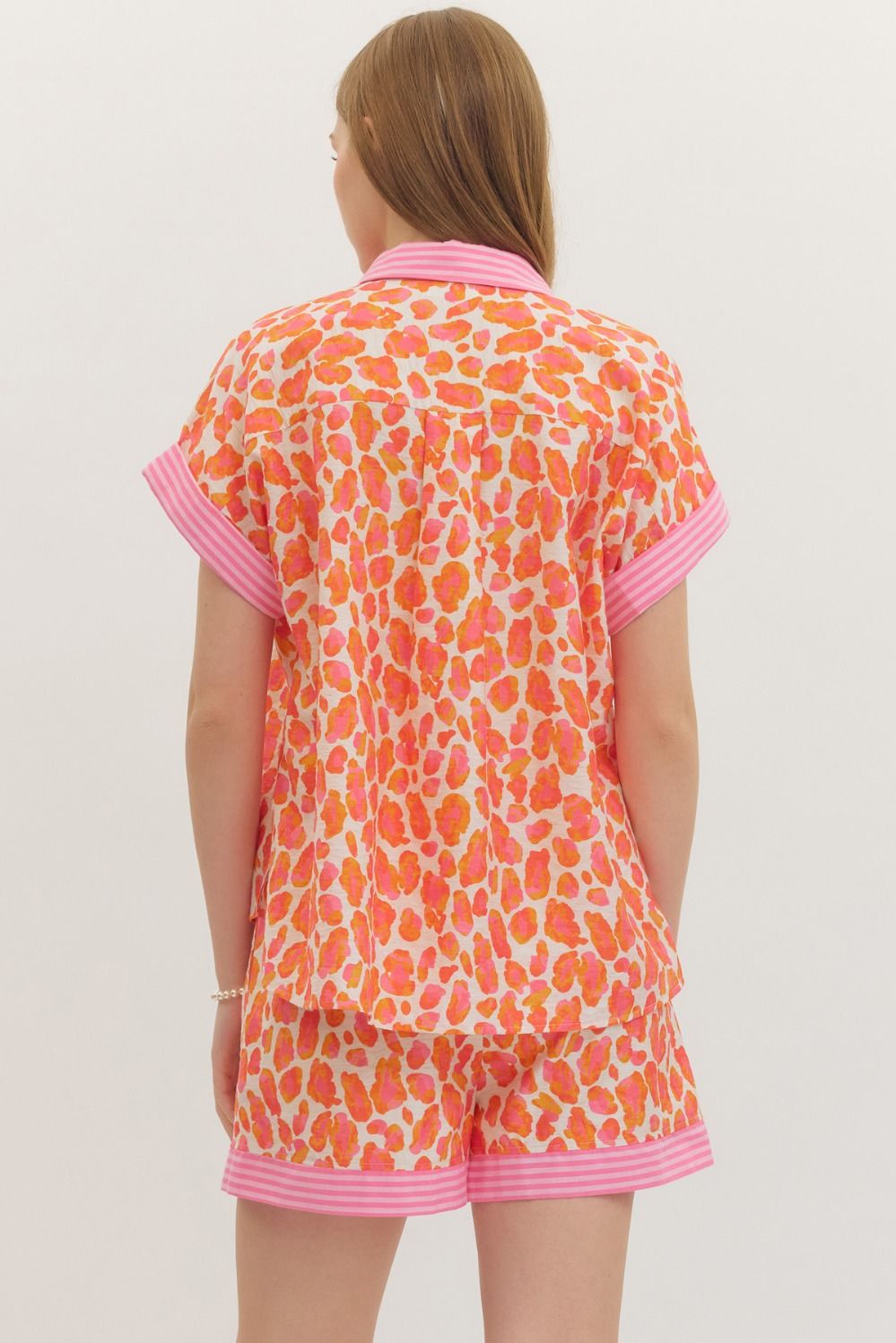 Person wearing a colorful outfit with pink trim on a plain background