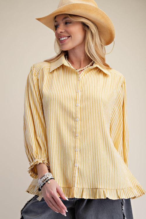 Woman wearing a yellow striped shirt and a straw hat against a beige background