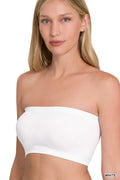 Woman wearing a white strapless top on a plain background