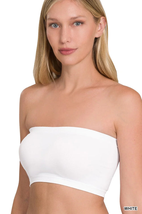 Woman wearing a white strapless top on a plain background