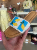 Hand holding a sandal with pineapple design in a store setting