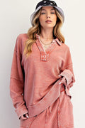 Woman wearing a pink oversized shirt and black and white bucket hat on a plain background
