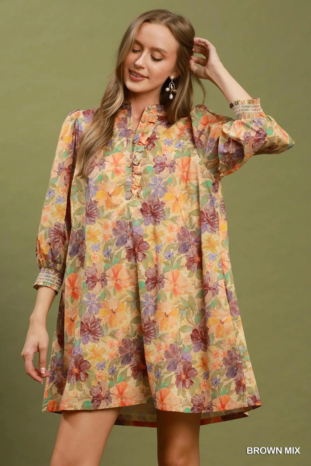 Woman wearing a colorful floral dress against a green background