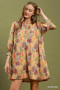 Woman wearing a colorful floral dress against a green background