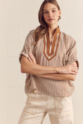 Woman wearing a striped shirt with a V-neckline against a light background