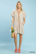 Woman wearing a striped dress holding flowers against a light blue background