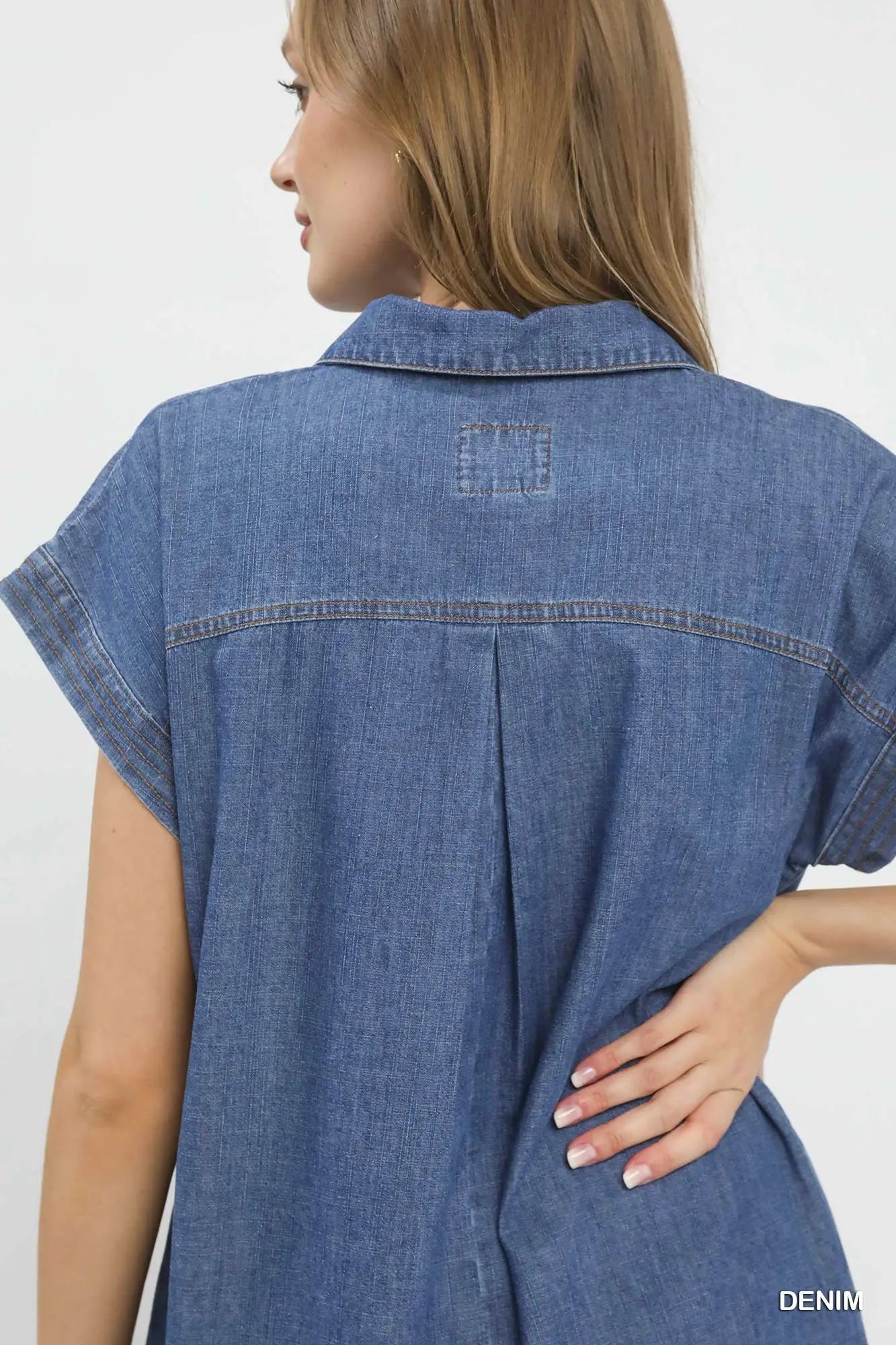 Woman wearing a blue denim dress with a plain background
