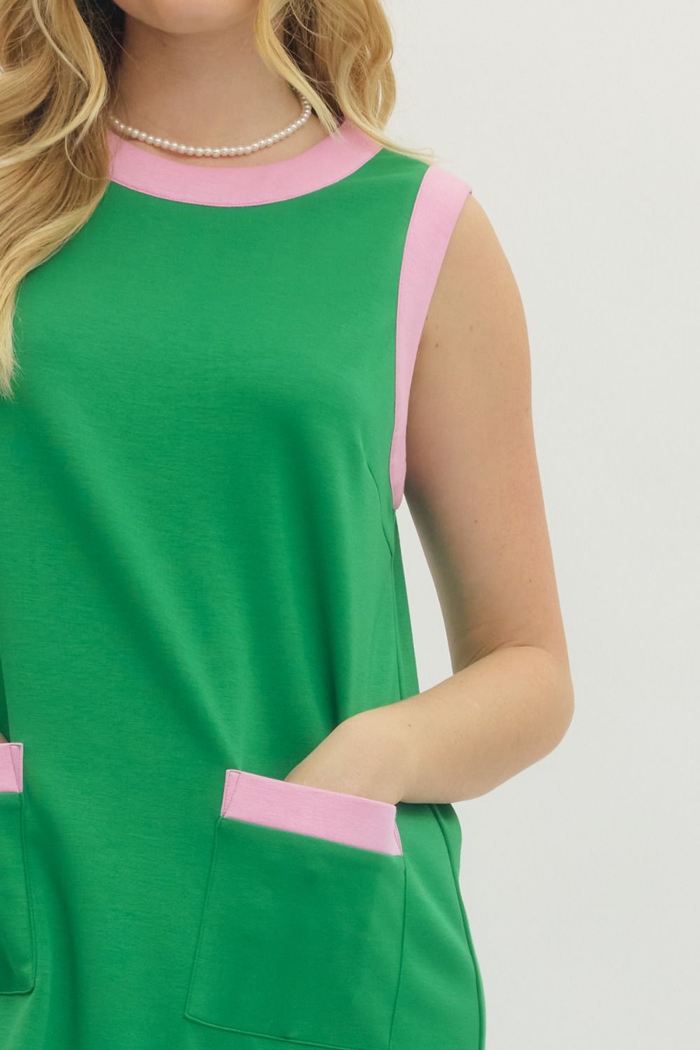 Green dress with pink accents worn by a person on a white background