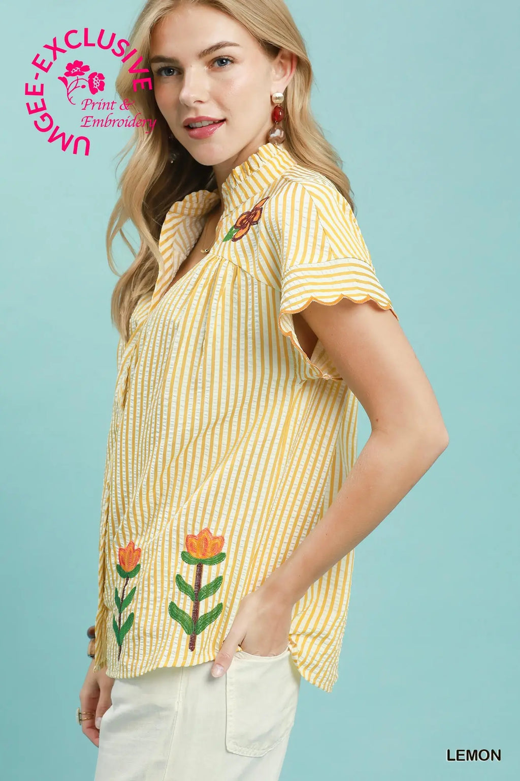 Woman wearing a yellow striped shirt with floral embroidery on a light blue background