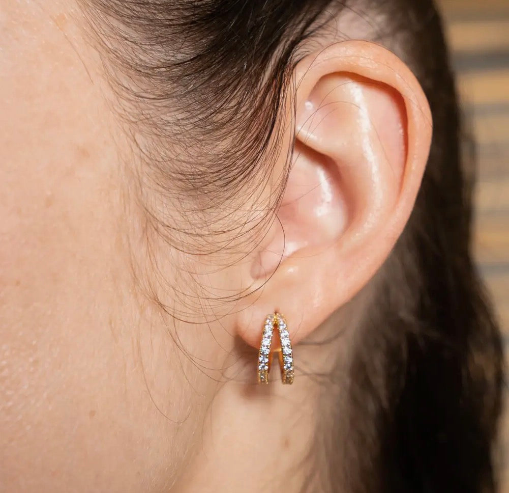 Close-up of an ear wearing a gold hoop earring with small stones.