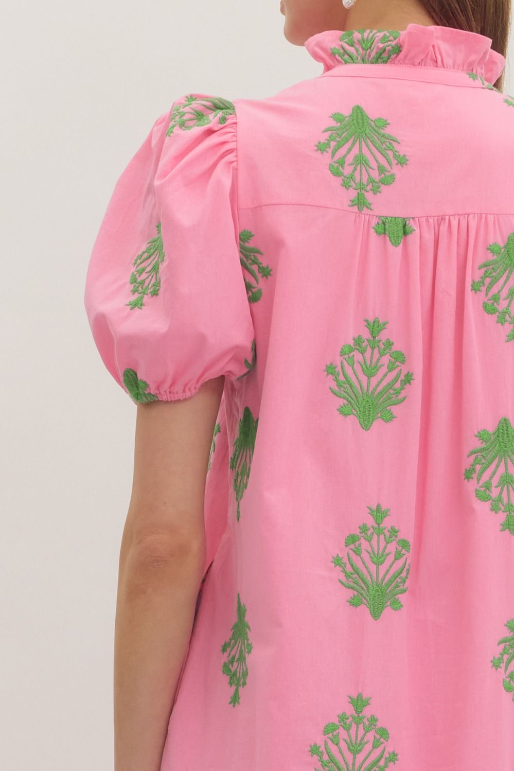 Pink dress with green patterns on a plain background