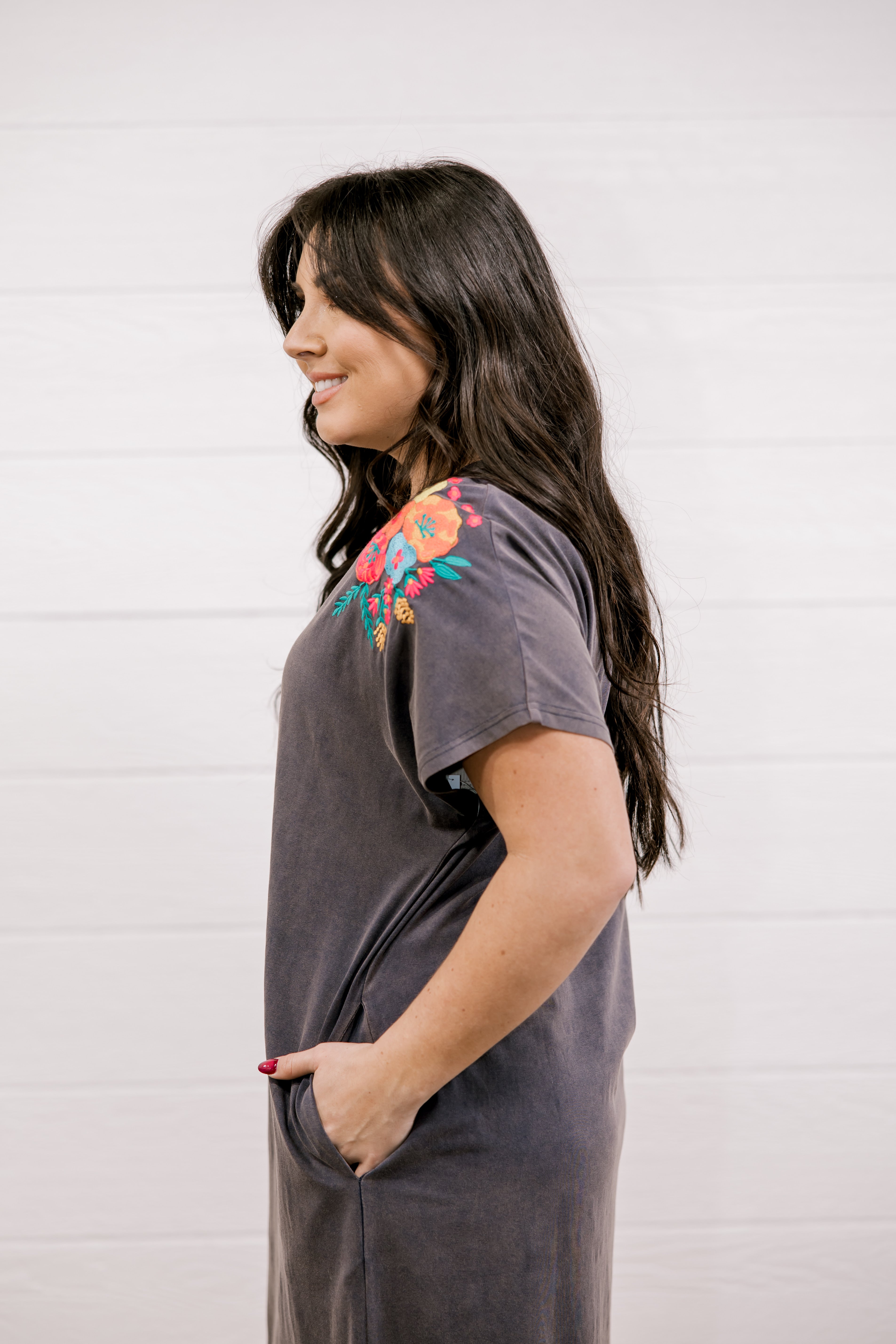 Woman wearing a gray t-shirt with floral embroidery on a white background