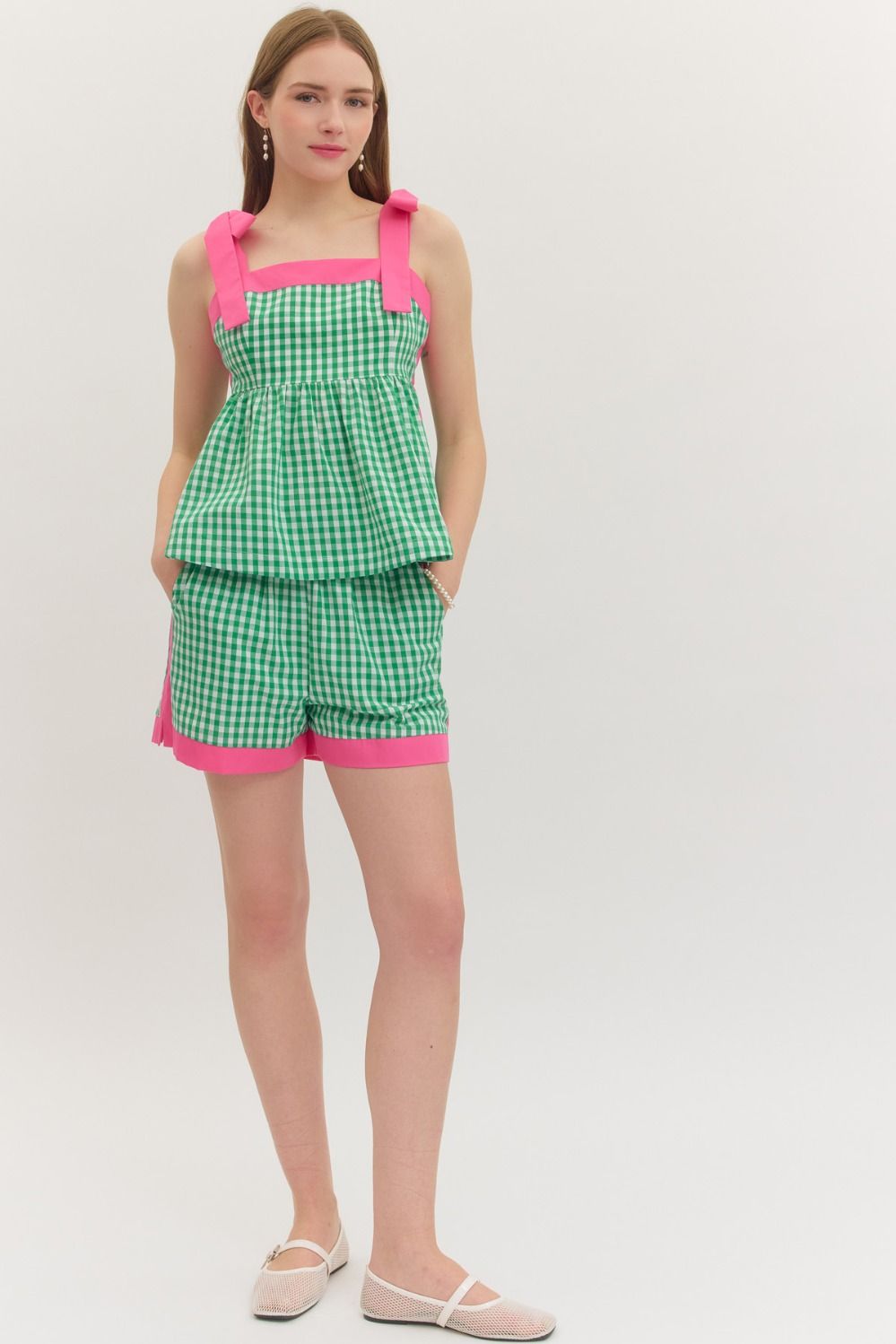 Woman wearing a green checkered outfit with pink accents on a white background