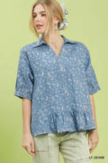 Woman wearing a light denim blouse with ruffled hem on a green background