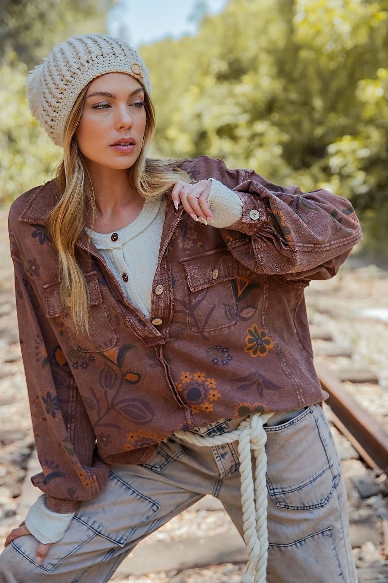 Woman wearing a brown floral jacket and beige knit hat outdoors.