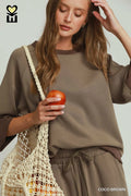 Woman holding an apple and a mesh bag on a plain background
