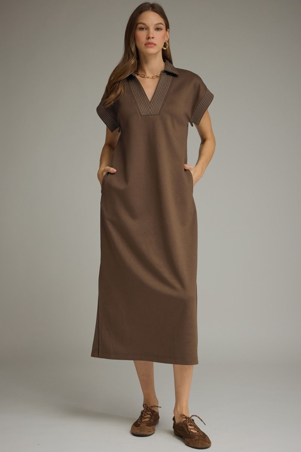 Woman wearing a brown dress against a neutral background